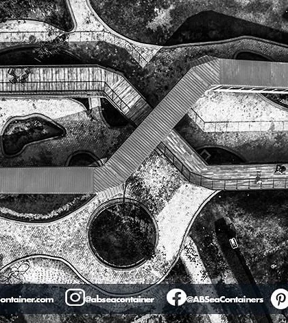 A black and white aerial view of 'Cafe Infinity' emphasizes the geometric forms and structural layout of the project. The interlocking containers create a unique architectural footprint.