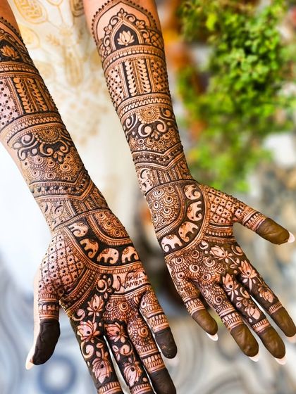 A full view of the symmetrical engagement henna, with matching designs on both hands and arms.