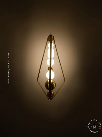 The triangular pendant light shown against a dark background, emphasizing its sculptural form and the warm light it emits. It's a perfect blend of geometric design and ambient lighting.