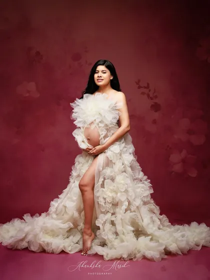 The combination of the cream floral gown against a deep pink, textured backdrop creates a rich and romantic visual story.