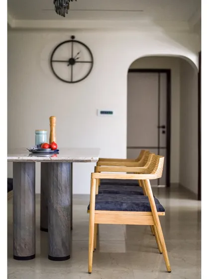 The dining area is simple and elegant, with a modern table and chairs and a large, minimalist clock on the wall.