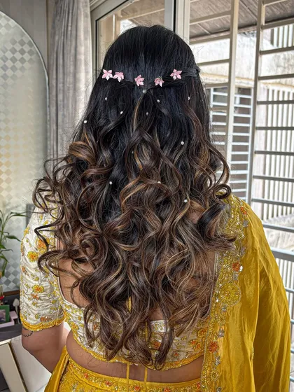 The hairstyle was soft, open curls with a braided detail, decorated with delicate pink flower clips.