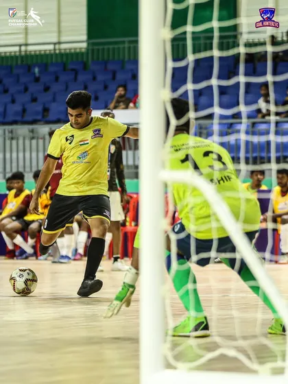 A player slotting the ball past the goalkeeper to score.