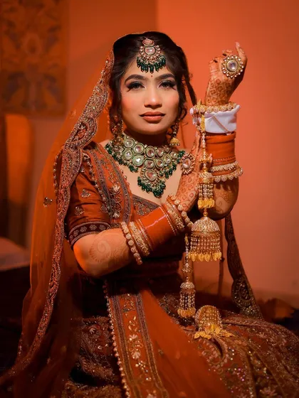 A three-quarter portrait of a bride holding her kalire, with warm, dramatic lighting.