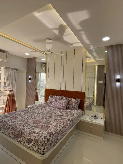 An evening view of the bedroom, where the warm ambient lighting from the false ceiling and wall sconces creates a cozy and inviting atmosphere.