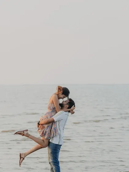 A classic, romantic lift against the backdrop of the sea and a soft sky. This is a timeless pre-wedding pose that captures the feeling of being swept off your feet.