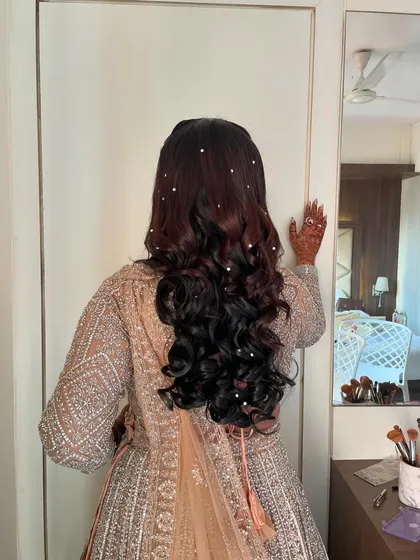 A reception hairstyle with soft curls and scattered pearl accessories for a touch of elegance.