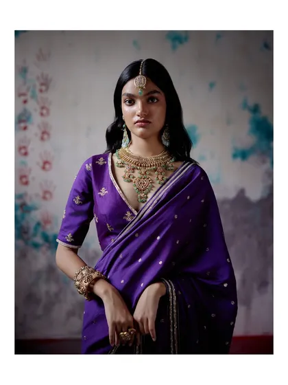 A regal purple saree with intricate gold embroidery and a deep V-neck blouse. Paired with traditional jewellery, this look is elevated, timeless, and perfect for a wedding ceremony.