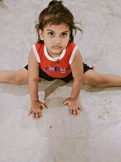 The same young student, holding her stretch with focus. This discipline will serve her well in karate and in life.