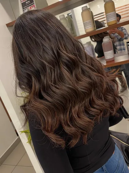 This balayage has rich chocolate and caramel tones. The soft waves add volume and show off the color variation.