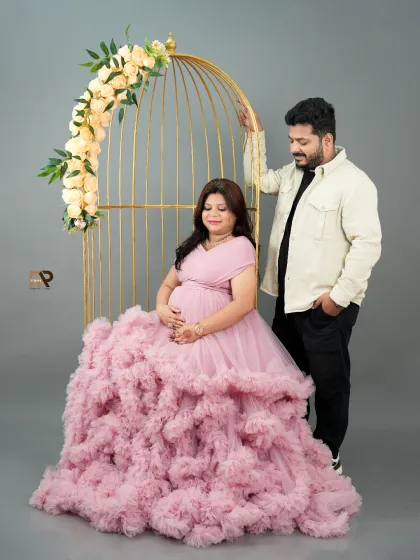 A vision in pink. This portrait uses a golden birdcage prop and a voluminous ruffled gown to create a whimsical and highly stylized maternity photo.