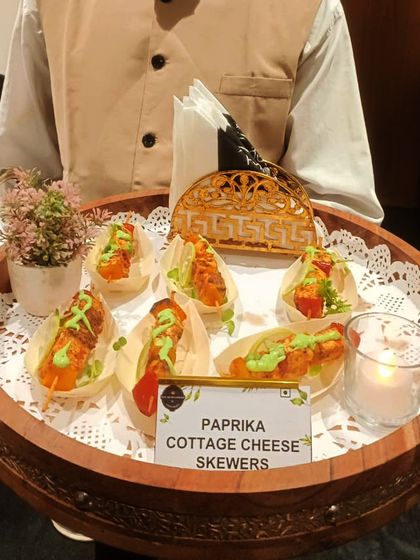 Paprika Cottage Cheese Skewers being served from a traditional wooden tray. The smoky paprika gives the soft paneer a wonderful flavour, drizzled with a cooling mint sauce.