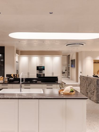 A wide view of the revamped Delhi showroom, showcasing multiple kitchen displays and a clean, modern aesthetic with soft, curved lighting elements.