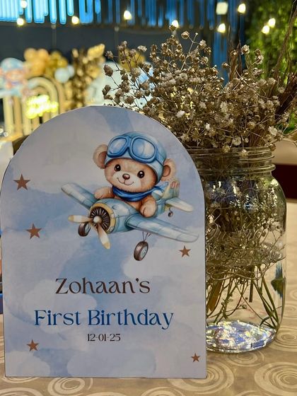 It's all in the details. This custom table menu card for Zohaan's first birthday features a cute teddy bear pilot, setting the stage for an adventurous airplane-themed celebration.