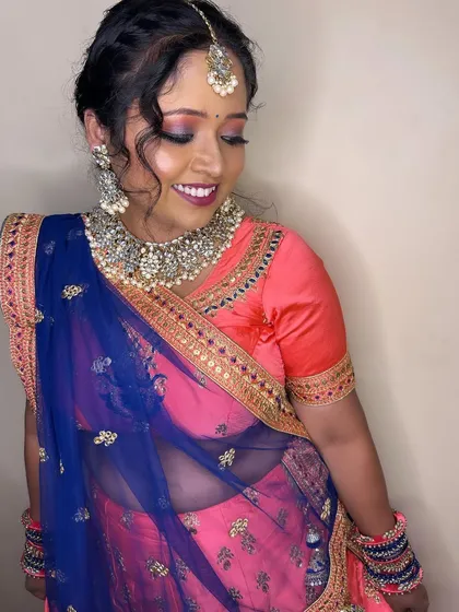 A smiling portrait of the bride, showing her complete look. The silver jewelry pairs beautifully with the cool tones of her lehenga.