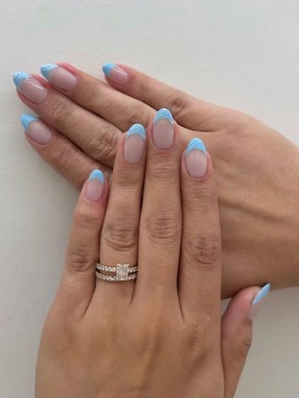 A fun twist on a classic, these almond-shaped nails feature baby blue French tips with a unique curved design.