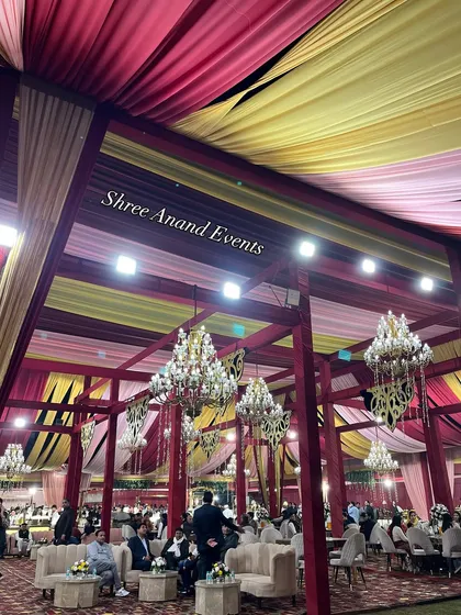 Looking up at the colorful draped ceiling of a massive event tent, filled with dozens of sparkling chandeliers.
