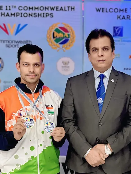 With one of our senior athletes, showcasing his medals from the 11th Commonwealth Karate Championship. My role is to guide our players at every step of their journey.