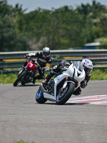 Two riders, one on a Triumph and one on a Royal Enfield, sharing the track during a session.