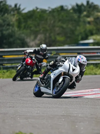 Two riders, one on a Triumph and one on a Royal Enfield, sharing the track during a session.