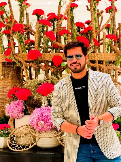 A stylish, casual look with a blazer, posing in front of a beautiful floral arrangement in Kolkata. My work takes me everywhere!