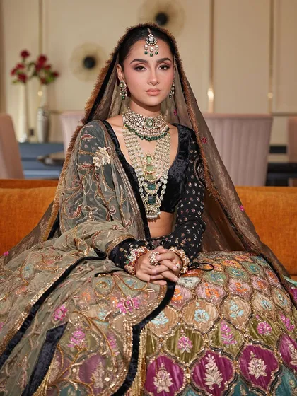 Seated gracefully, this bride showcases her unique and colorful bridal lehenga. Her makeup is subtle, with a focus on enhancing her natural features to create a look of timeless beauty.