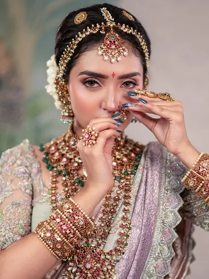 The eyes are the silent storytellers. This pose, with hands framing the face, draws attention to the model's expressive eyes and the intricate details of her jewelry and nail art.