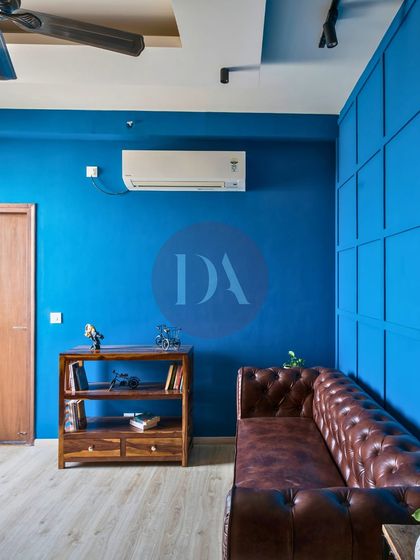 An angled view of the bold blue room, showing how the color envelops the space. The warm wooden bookshelf provides a beautiful contrast, grounding the vibrant hue.
