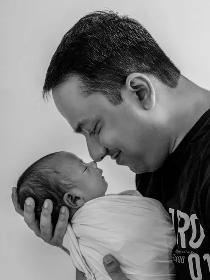 An intimate black and white portrait of a father and his newborn baby, nose to nose, capturing the profound and gentle connection in those very first days.