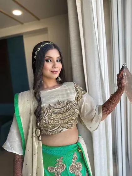 A soft glam look for a Mayra ceremony. The bride's green and cream outfit is paired with natural makeup and loose, wavy hair.