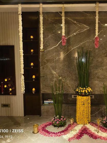 An elegant indoor Diwali decoration, featuring floral rangoli, candle arrangements, and hanging garlands of jasmine.