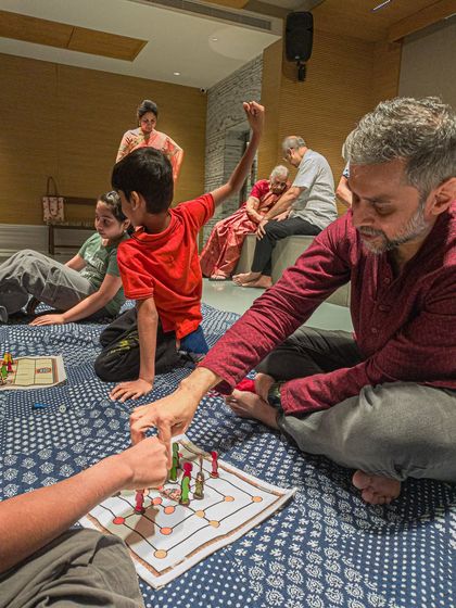 A father and son playing a traditional board game on the floor during a family event.