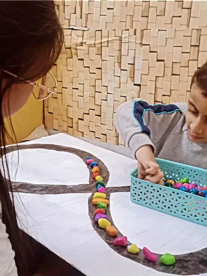 Our ABA therapy sessions use structured play to achieve specific goals. In this activity, the child is developing fine motor skills and pattern recognition by placing colorful stones along a path, improving focus in a calm setting.
