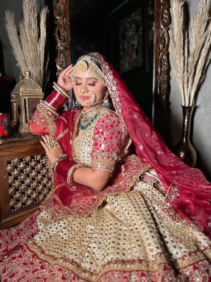 This bride is wearing a classic Sabyasachi-inspired ivory and red lehenga. The look is completed with a heavy choker, matha patti, and red bridal bangles, all available for rent.