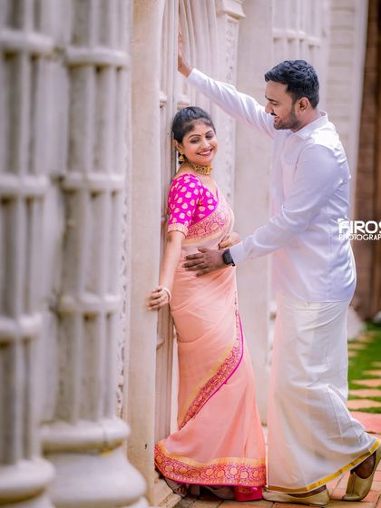 An intimate moment for a couple in traditional wear against a wall of white pillars.