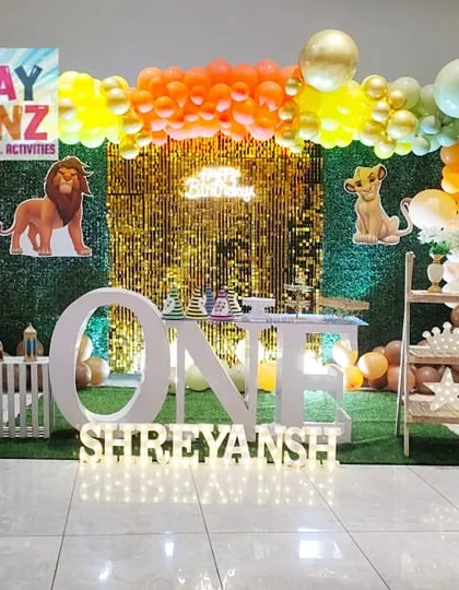 I designed this entire Lion King theme setup for a first birthday party. It features a lush green backdrop, a sparkling sequin panel, character cutouts of Simba and his friends, and large marquee letters spelling "ONE" to create a complete photo-ready stage.