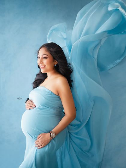 A beautiful profile shot against a hand-painted blue backdrop. The flowing fabric adds a layer of softness and movement to the image.