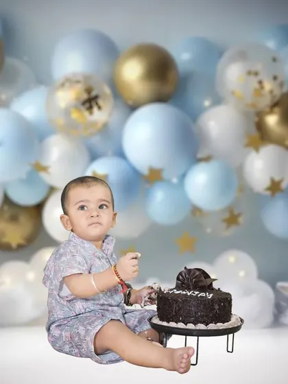A baby boy enjoys his first taste of cake in this cake smash setup. We offer fun cake smash sessions with customized backdrops for first birthdays.