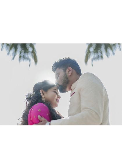 A beautifully backlit shot of the groom kissing the bride's forehead, creating a dreamy and romantic silhouette.