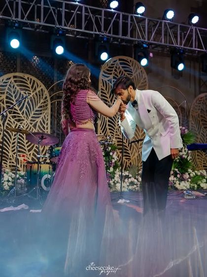 A classic, chivalrous moment during the couple's Sangeet dance performance, complete with stage smoke for a dreamy effect.