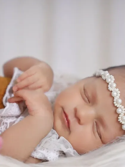 Sometimes, the most beautiful photos are the simplest. This close-up highlights the delicate features of a sleeping newborn, from her soft skin to the tiny pearls on her headband. It’s these small details I want you to remember forever.