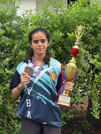 One of our star players, Nischitha, holding her bronze medal and the team trophy. We celebrate individual contributions that lead to team success.