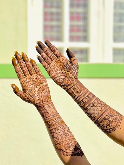 The beautiful stain of an intricate bridal design, captured in bright sunlight. The patterns include elephants, lotuses, and geometric checks.