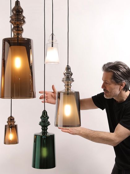 Designer Matteo Ugolini presents the Alibaglass collection, showcasing the variety of colors and sizes available. This image highlights the human touch and design thinking behind these beautiful glass pendants.