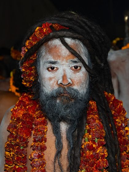 A close-up portrait of a Naga sadhu at the Kumbh Mela. His dreadlocks are piled high, and his face, covered in ash, carries a serene and powerful presence.