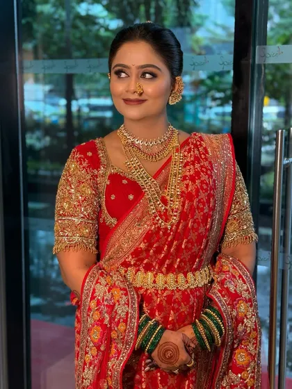 A classic red saree look for a Maharashtrian bride, complete with gold jewellery and a radiant smile.
