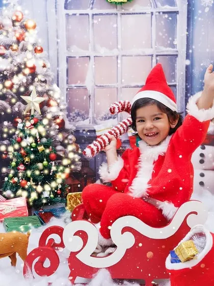 Waving hello from Santa's sleigh! This little girl in a Santa costume is ready to deliver presents in this fun and interactive Christmas photo.