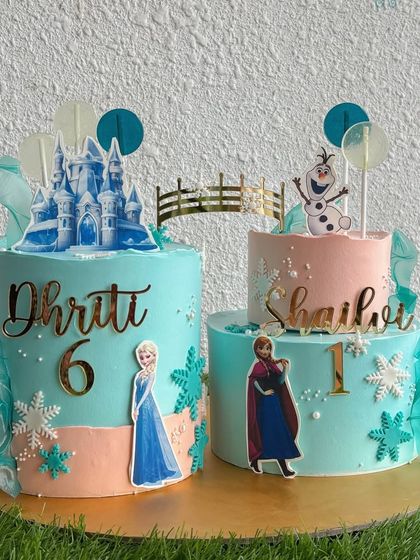Perfect for sisters, these Frozen-themed twin cakes feature Elsa and Anna in their winter wonderland. We customized the design with each sister's name and age, connecting the two cakes with a delicate bridge.