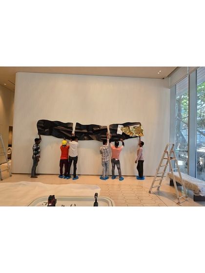 The team works together to lift and position the large, heavy panels of the steel sculpture.
