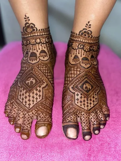 A geometric foot mehandi with a central diamond pattern featuring an elephant motif, surrounded by intricate line and dot work.